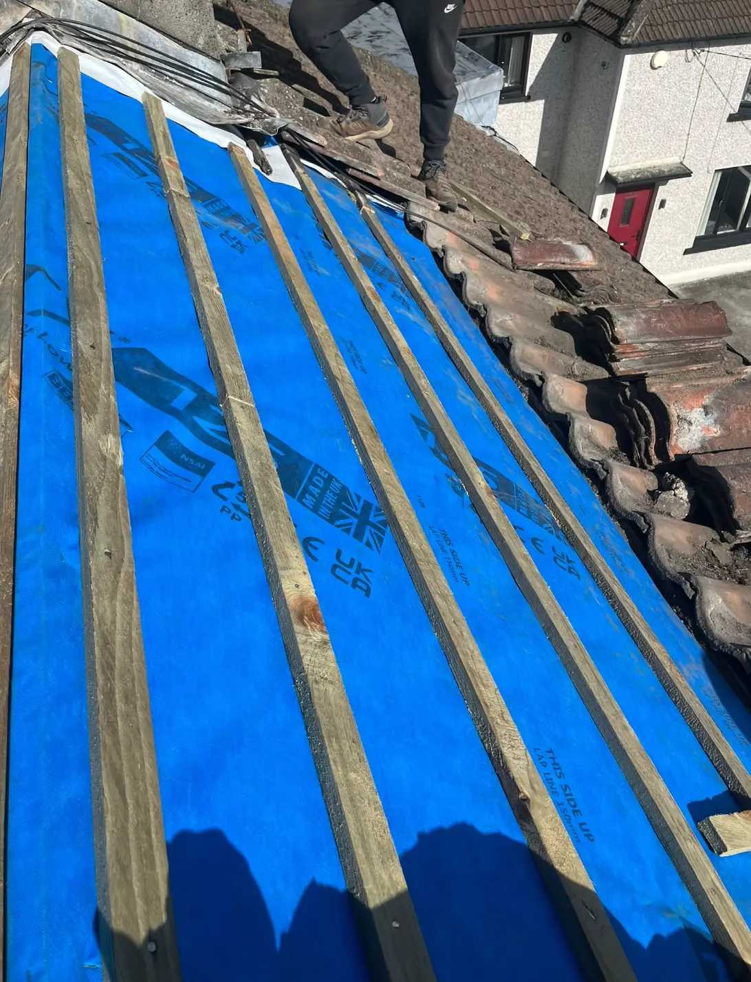 Blue roofing membrane fixed beneath timber battens on a pitched roof
